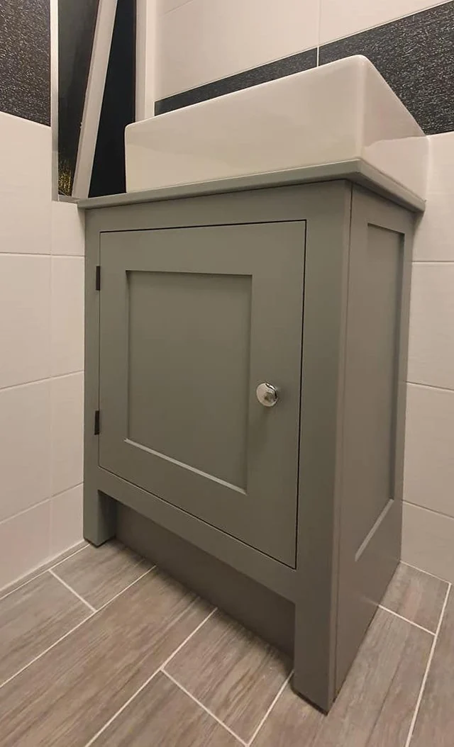 Sage painted bathroom vanity supporting a white basin