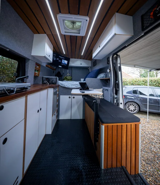 Interior of camper conversion with timber ceiling and fitted cabinetry